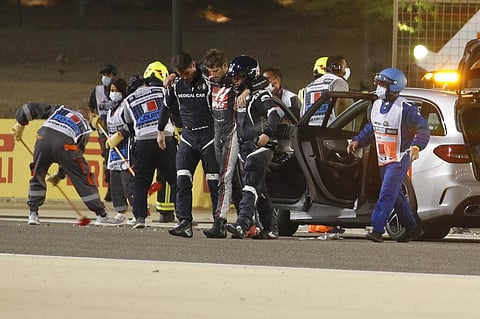 Haas driver Romain Grosjean of France is helped by medical staff after he crashed his car during the Formula One race in Bahrain International Circuit. (Photo | AP)