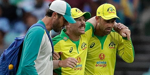 Australia's David Warner (C) is assisted from the field after injuring himself while fielding during the ODI match against India at the Sydney Cricket Ground. (Photo | AP)