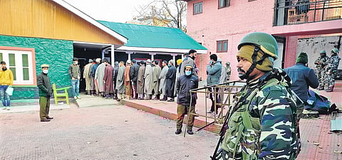 A security official keeps a vigil as people cast their votes for the District Development Council election in Srinagar. (Photo | PTI)