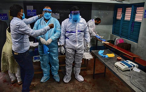 Election staff donning PPE kit wait for COVID patients to cast their ballot for RR Nagar Bypoll at BET College in Bengaluru. (Photo | Shriram BN, EPS)