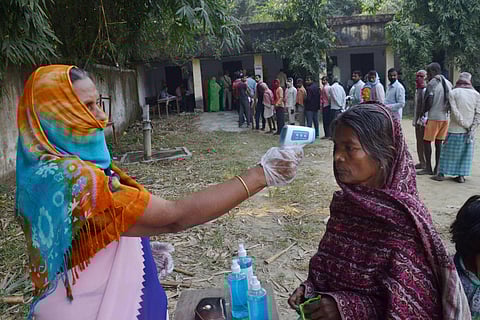 Voters undergo thermal screening at a polling station as they arrive to cast their votes. (Photo| PTI)