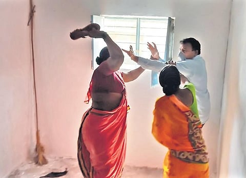 Kalavathi, a farmer, attacks the Tamsi mandal VRO with a slipper on Tuesday, alleging that he had reduced the extent of her land
