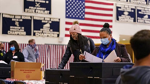 Two women, wearing protective masks due to the COVID-19 virus outbreak, cast their ballots at a polling station at Windham, N.H. High School. (Photo | AP)