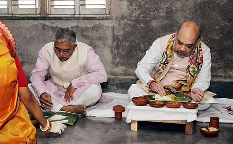 Home Minister Amit Shah and BJP State President Dilip Ghosh eat lunch with a Matua family at their residence at Gouanganagar in Kolkata (Photo | PTI)