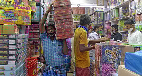 A man carries packets of firecrackers for display at a shop on the eve of Diwali in Chennai. (Photo | Martin Louis, EPS)