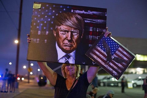 A President Donald Trump supporter holds up a painting of him outside of the Maricopa County Recorder's Office where votes in the general election are being counted in Phoenix, Friday, Nov. 6, 2020. (