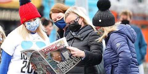 Residents read a copy of their local paper in the town of Ballina, North West of Ireland, the ancestral home of President elect Joe Biden. (Photo | AP)