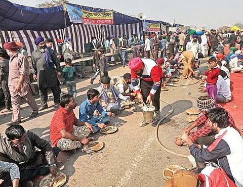 Farmers eat food at the Singhu border during their ongoing 'Delhi Chalo' protest against the Centre's new farm laws in New Delhi. (Photo | Shekhar Yadav, EPS)