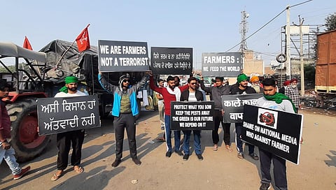 Farmers hold placards during their ongoing Delhi Chalo agitation against the new farm laws, at Singhu border on Tuesday. (Photo | Shekhar Yadav, EPS)
