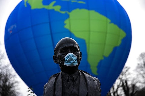 The bust of French statesman Robert Schuman, one of the founders of European Union, is seen while environmental activists launch a hot air balloon during a demonstration in Brussels. (Photo | AP)