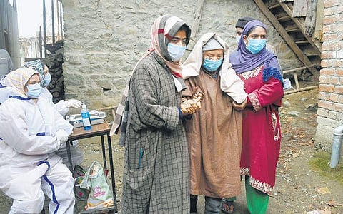 An elderly voter being escorted by her daughters as she arrives to cast her vote in DDC elections, at Wakura. (Photo | PTI)