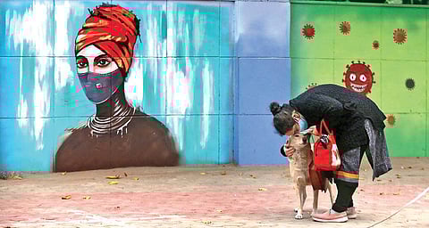 A woman wearing a mask walks past a mural on novel coronavirus in New Delhi. (File photo| Shekhar Yadav, EPS)