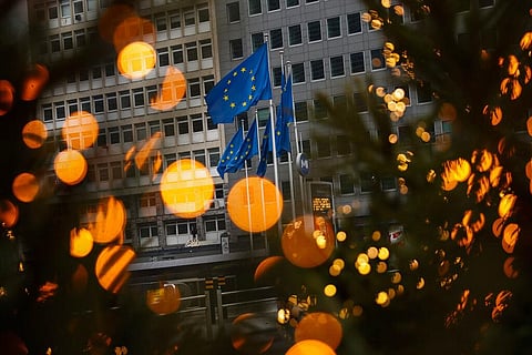 European Union flags, seen through Christmas decoration lights, flutter in the wind outside the European Commission headquarters in Brussels. (Photo | AP)