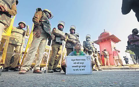A farmer sits with a placard after being stopped by Haryana police. (Photo | Shekhar Yadav, EPS)