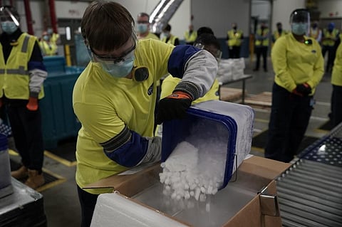 A worker pours dry ice into boxes containing the Pfizer-BioNTech Covid-19 vaccine. (Photo | AFP)