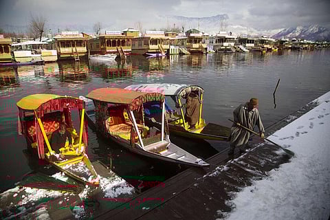 A Kashmiri boatman clears snow after parking his boat in the Dal Lake after overnight snowfall in Srinagar. (Photo | AP)