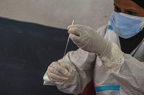 A health worker wearing a PPE kit collects a sample for COVID-19 Rapid Antigen test at Kursoo Rajbagh in Srinagar. (File Photo | PTI)