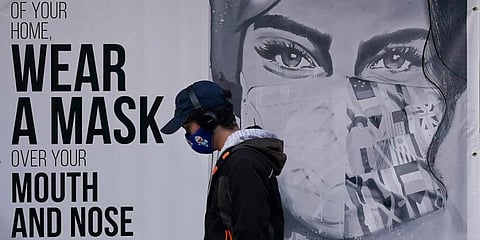 A pedestrian walks past a mural reading: 'When out of your home, Wear a mask over your mouth and nose,' during the coronavirus outbreak in San Francisco. (Photo | AP)
