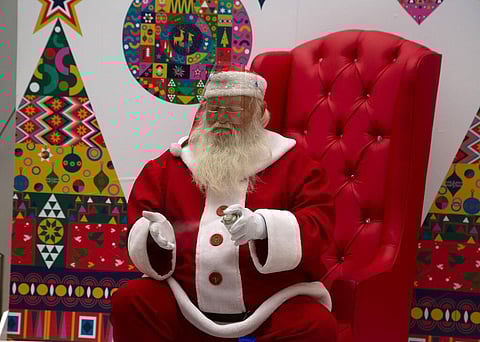 A man dressed as Santa Claus sanitizes his gloved hands, to protect against COVID-19, during a day of being photographed with children at a shopping mall in Johannesburg. (Photo | AP)