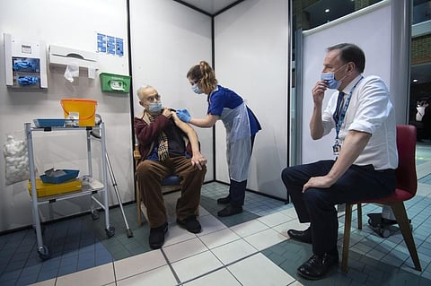 Simon Stevens (R), Chief Executive of the NHS, watches as a nurse administers a dose of the Pfizer-BioNTech Covid-19 vaccine to Frank Naderer (C), 82, at Guy's Hospital in London. (Photo | AFP)