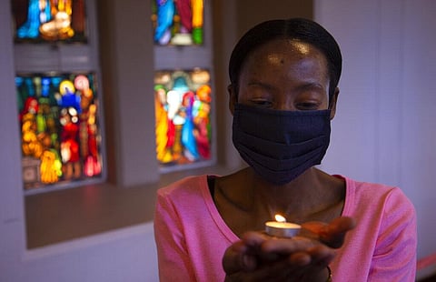 A worshipper wearing a face mask, holds a lit candle prior to a morning Christmas Mass at the Rosebank Catholic Church in Johannesburg, Friday. (Photo | AP)