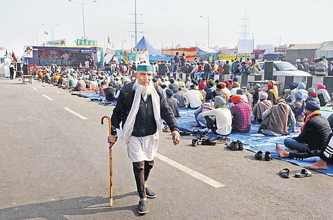 AAP MPs Sanjay Singh and Bhagwant Mann display placards as they protest over farmers’ issues in the Central Hall of Parliament on Friday; farmers at the Ghazipur border on 30th day of their protest