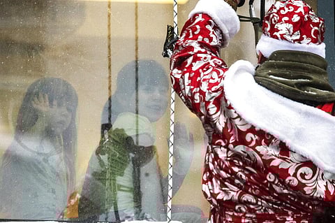 A Russian emergency rescue worker dressed as Ded Moroz (Santa Claus greets children as he scales the wall of a children hospital to mark the upcoming New Year celebrations. (Photo | AP)