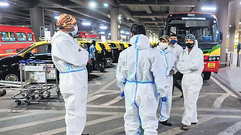 Passengers wearing PPE kits wait at arrival area of Mumbai airport. (Photo | PTI)