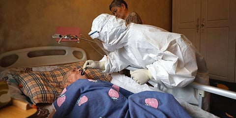 A medical worker takes a swab from a resident for a coronavirus test during home visits in Wuhan. (Photo | AP)