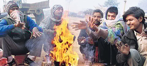 People sit around a bonfire to warm themselves during a cold and foggy morning in Gurugram. (Photo | PTI)