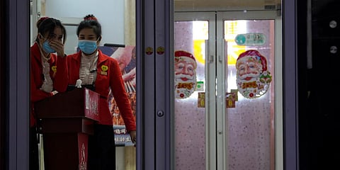 Chinese workers wait for customers at the entrance to a restaurant in Beijing. (File photo| AP)
