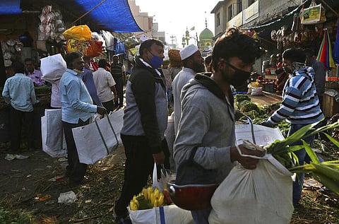 Shoppers wearing face masks as a precaution against the coronavirus navigate their way through a crowded market area in Bengaluru, India. (Photo | AP)