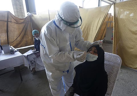 A health worker takes a nasal swab sample at a screening center for coronavirus, in Lahore, Pakistan. (Photo| AP)