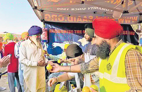 Amarpreet Singh distributes fruits at the Khalsa Aid stall to farmers at the Singhu border;