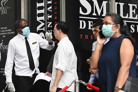 Building management staff conduct temperature screenings of visitors and tenants of a building in the financial district of Singapore. (File photo| AFP)
