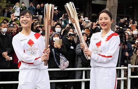A torchbearer and actress Satomi Ishihara (R), one of the official ambassadors of the Tokyo 2020 torch relay, pose with the olympic torch. (Photo | AFP)