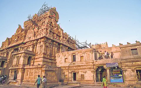 Visitors at the temple look at workers engaged in restoration work