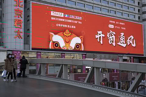 In this photo taken Saturday, Feb. 22, 2020, shoppers walk near a mall display with the government slogan 'Open windows and allow air to flow' in Beijing, China. (Photo | AP)