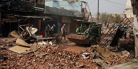Delhi municipal workers remove bricks and rocks from a street vandalized in Tuesday's violence in New Delhi. (Photo | AP)