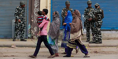 An family walks past paramilitary soldiers guarding a street following violence in New Delhi. (Photo | AP)