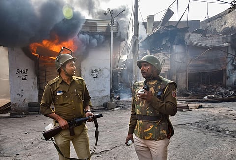 Security personnel stand near a burning shop following clashes over the new citizenship law, in Gokulpuri area of northeast Delhi. (Photo | PTI)