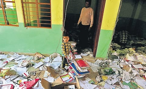 A child collects books at a school vandalised in Shiv Vihar. (PHOTO | SHEKHAR YADAV, EPS)