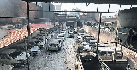 Charred vehicles at a parking lot near Usmanpur; a woman watches policemen; firemen at Gokulpuri; a family on scooter passes by security personnel at Baburpur | (PHOTO | SHEKHAR YADAV, EPS)