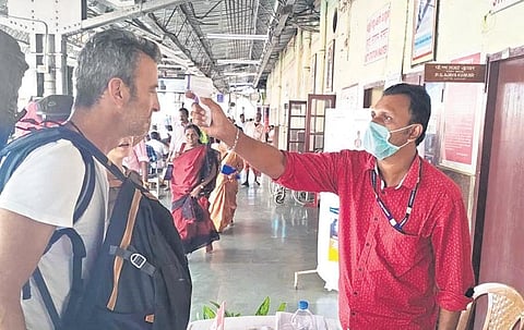 A foreign passenger being monitored with a flash thermometer for nCoV symptoms at the Corona Correctional Corner at Kollam railway station on Friday | express