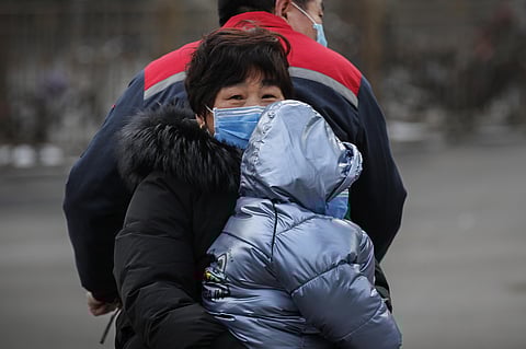 A Chinese families wearing masks ride on a tricycle on a street in Beijing, Saturday, Feb. 8, 2020. (Photo | AP)