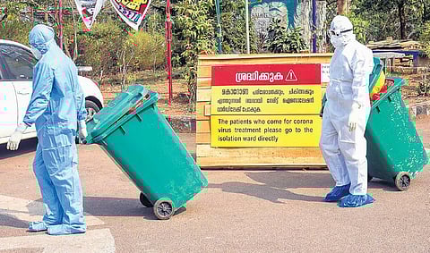 Medical staff, wearing protective suits, hold medical waste as they exit the Special Isolation Ward set up to provide treatment to novel coronavirus patients at Kochi Medical college, in Kerala | PTI