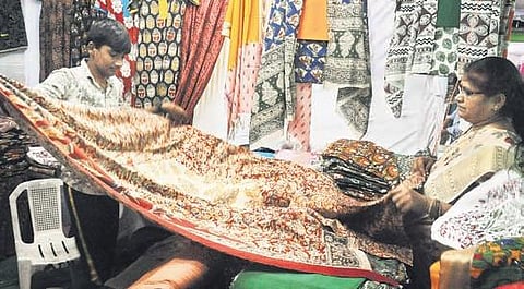 A customer being shown Kalamkari block-printed sarees at Lepakshi expo in Vijayawada on Saturday. (Photo| EPS/ Prasant Madugula)