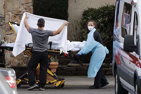 A staff member blocks the view as a person is taken by a stretcher to a waiting ambulance from a nursing facility where more than 50 people are sick and being tested for the COVID-19 virus, Saturday, Feb. 29, 2020, in Kirkland, Wash. (Photo | AP)