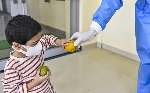 A child who was tested negative for the novel coronavirus is offered a fruit by a medic at the ITBP quarantine facility. (Photo | PTI)