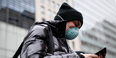 A pedestrian uses her phone while wearing a face mask in Herald Square, Thursday, March 12, 2020, in New York. (Photo | AP)